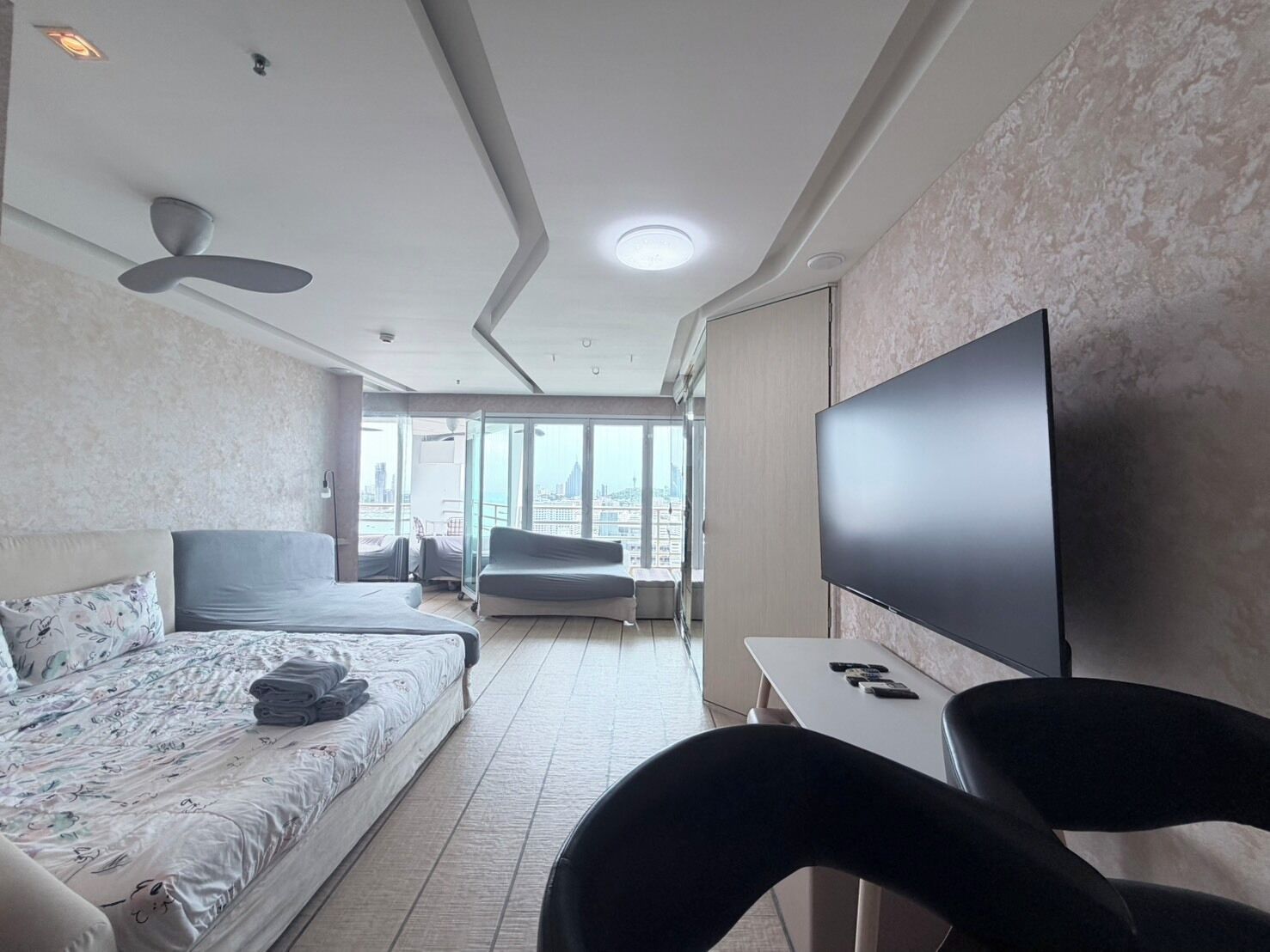 A hotel room with a bed, a sofa, a TV, and a view of the city.