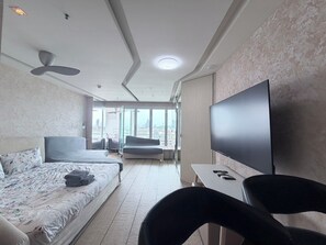 A hotel room with a bed, a sofa, a TV, and a view of the city.