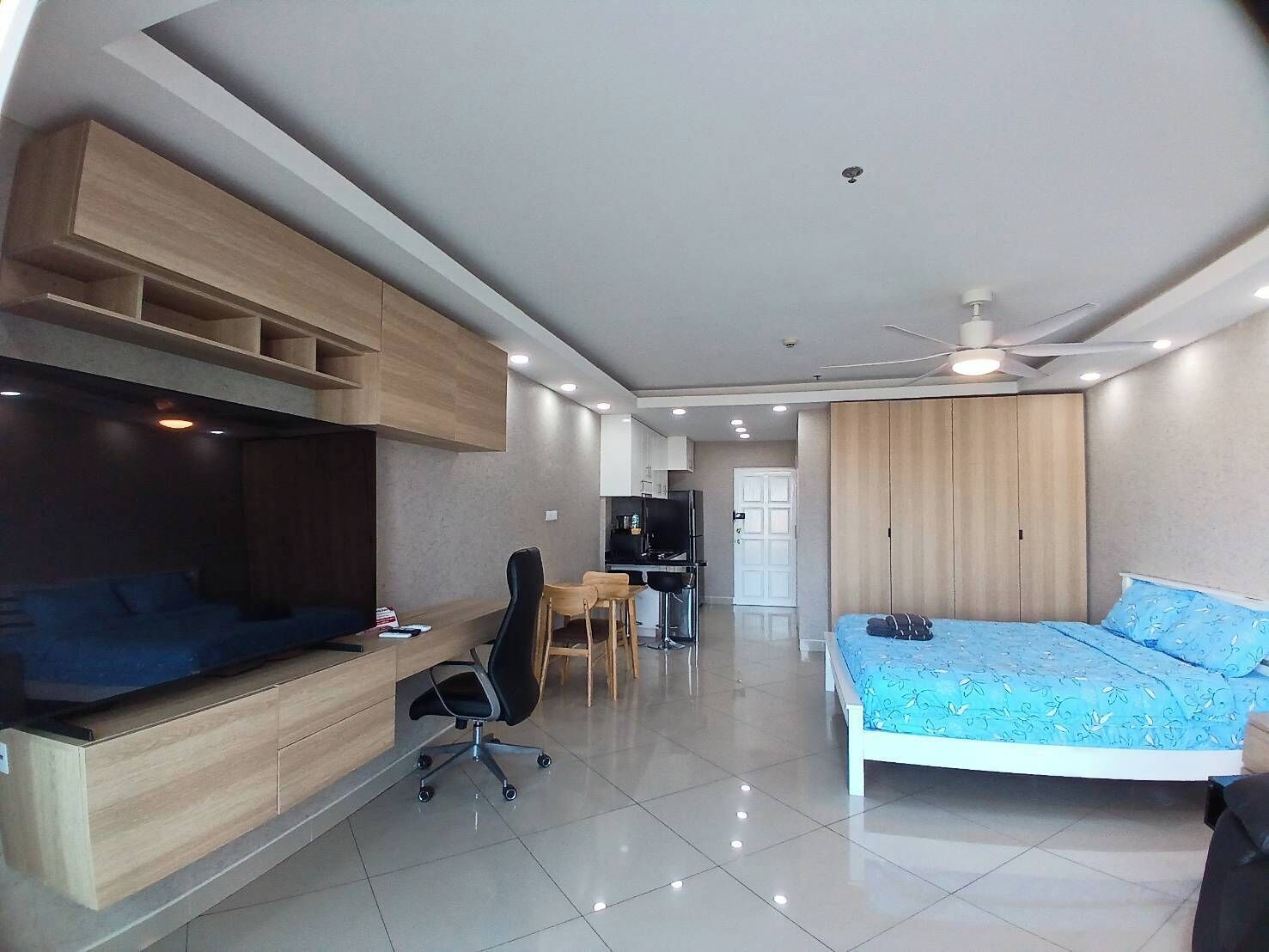Ein modernes Schlafzimmer mit Bett, Schreibtisch, Fernseher und Einbauschränken.