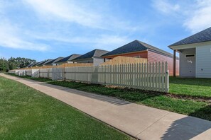 A row of single-story houses with a wooden picket fence, a concrete pathway, and a grassy lawn. - Spacious New Home 3BR/2BA Remote-Work Ready Dogs ok, fenced yard Near Lafayette (Duson)