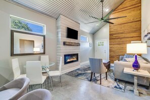 A modern living room with a fireplace, a ceiling fan, and a large window. - Spacious New Home 3BR/2BA Remote-Work Ready Dogs ok, fenced yard Near Lafayette (Duson)