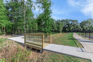 A park with a wooden bench, paved walkways, and a metal fence. - Spacious New Home 3BR/2BA Remote-Work Ready Dogs ok, fenced yard Near Lafayette (Duson)