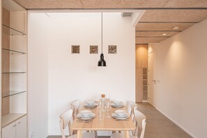 A dining area with a table set for four, chairs, a hanging light fixture, and a door leading to a hallway. - Majordoms Llimoner 2 – Figueres (Figueres)