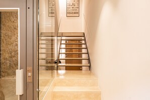 A modern interior with a glass elevator door, a metal staircase, and a wall-mounted informational display. - Majordoms Llimoner 2 – Figueres (Figueres)