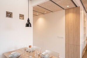 A dining area with a table set for four, a pendant light, and a wooden cabinet.