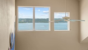 A room with two windows overlooking a body of water, a ceiling fan, and a partial view of a painting on the wall. - Club Yakov & 3bdr Lakefront (Hollister)