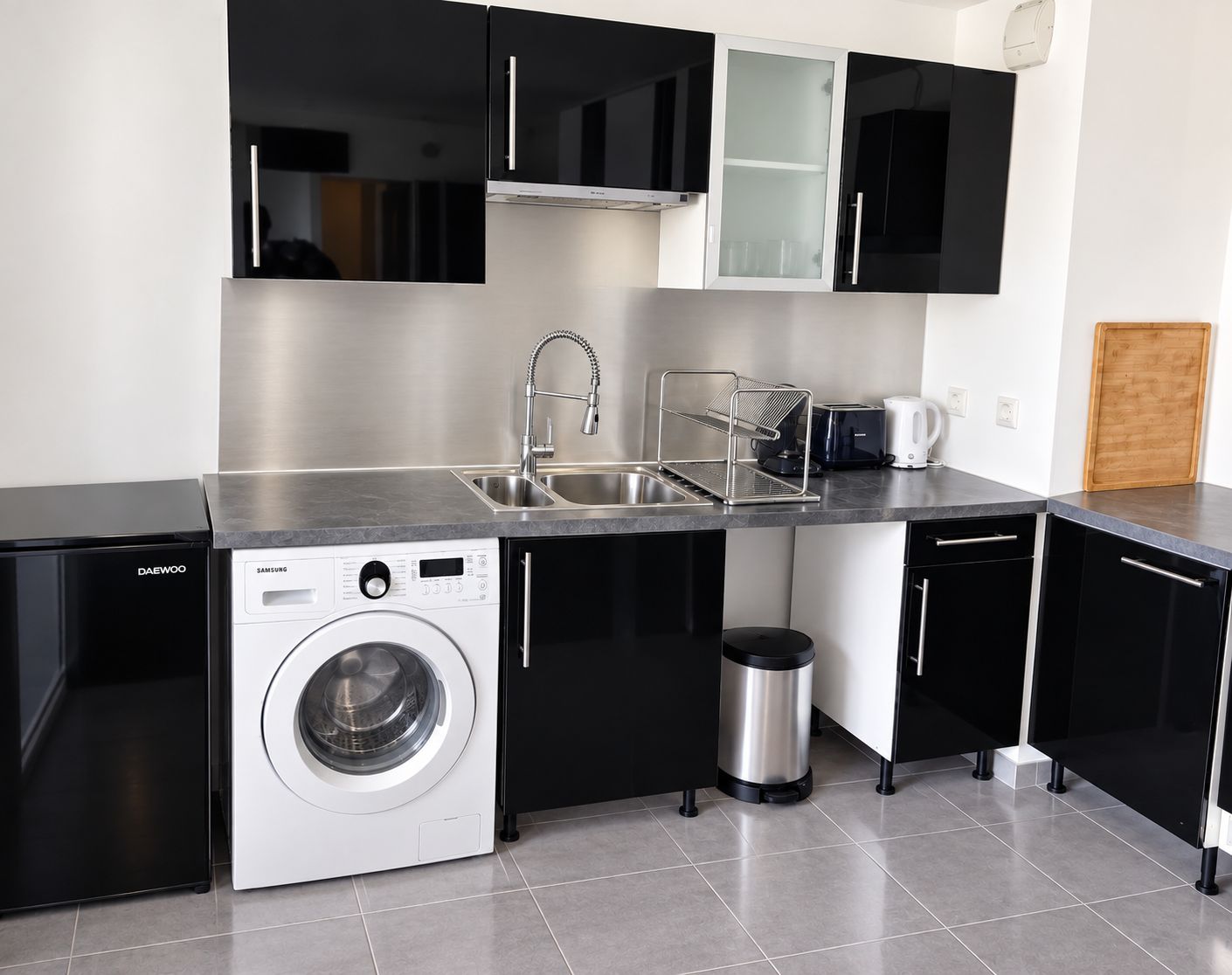 Una cocina moderna con lavadora integrada, lavavajillas y pileta de acero inoxidable.