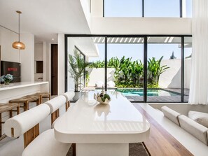 A modern kitchen with a built-in oven and a dining area with a pool view. - Casa Rio | 3BR Enclosed Living & Pool (Kuta Utara)