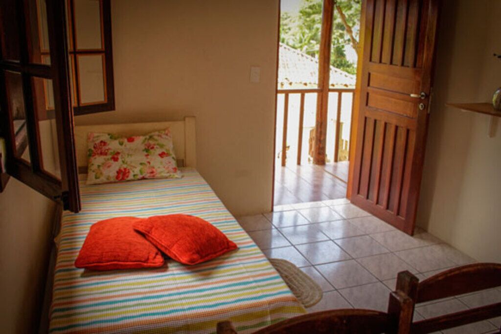 Una habitación con una cama, una puerta de madera y vistas al exterior.