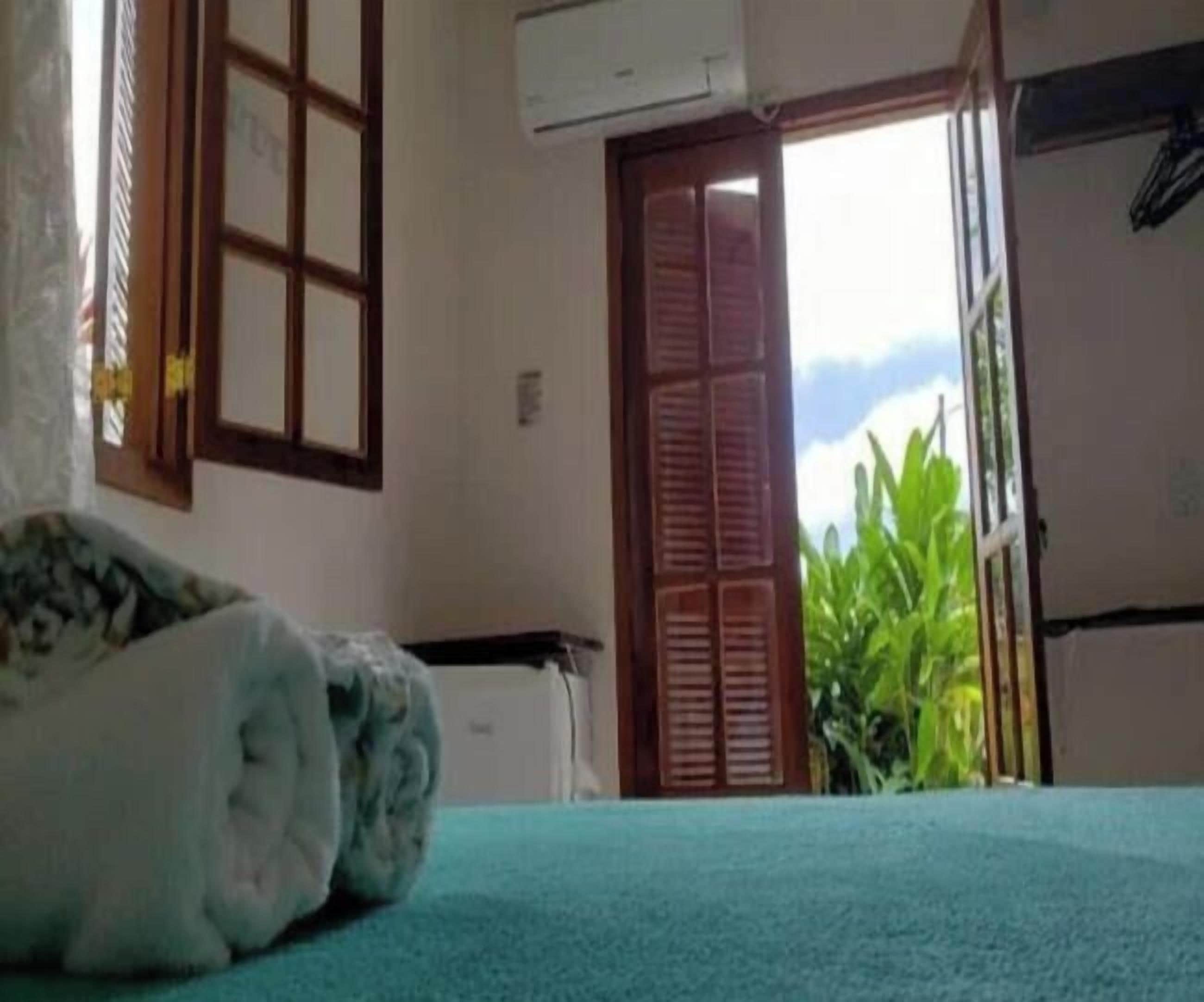 A room with a bed, a window with a view, and a door leading outside.