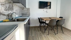 Une cuisine compacte équipée d’une cuisinière intégrée, d’un évier et d’un coin repas avec une table et des chaises.