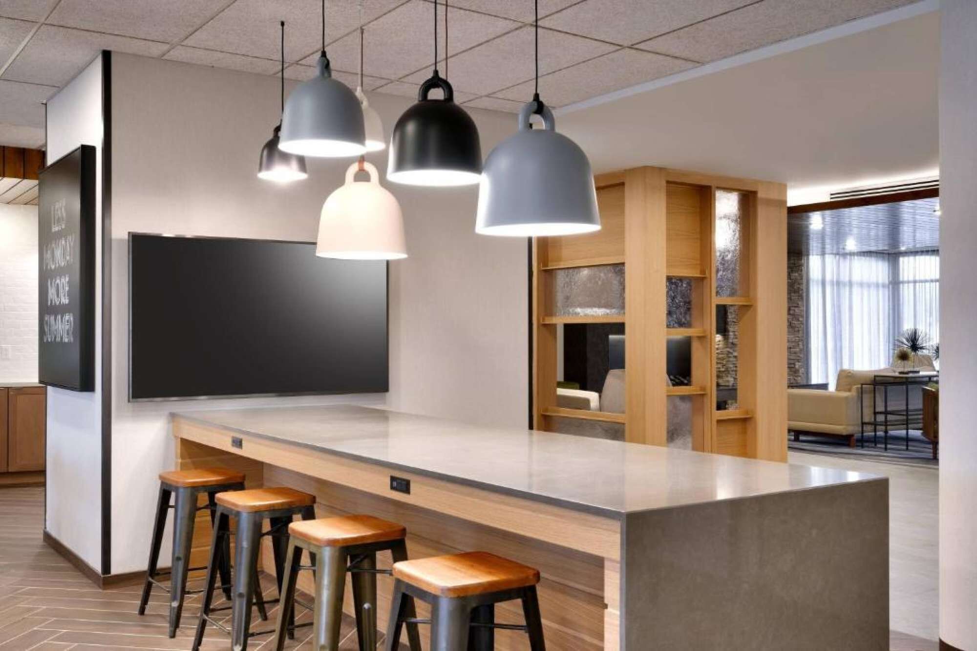 A modern kitchen with a bar area, bar stools, and pendant lighting.
