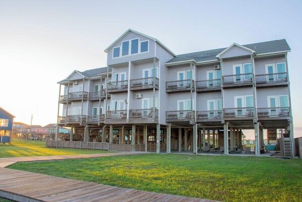 A multi-story hotel with balconies, a wooden deck, and a grassy area.