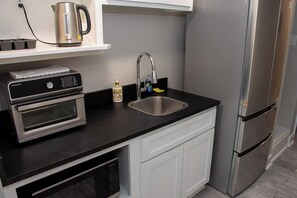A kitchen with a built-in oven, a coffee maker, a sink, and a refrigerator.