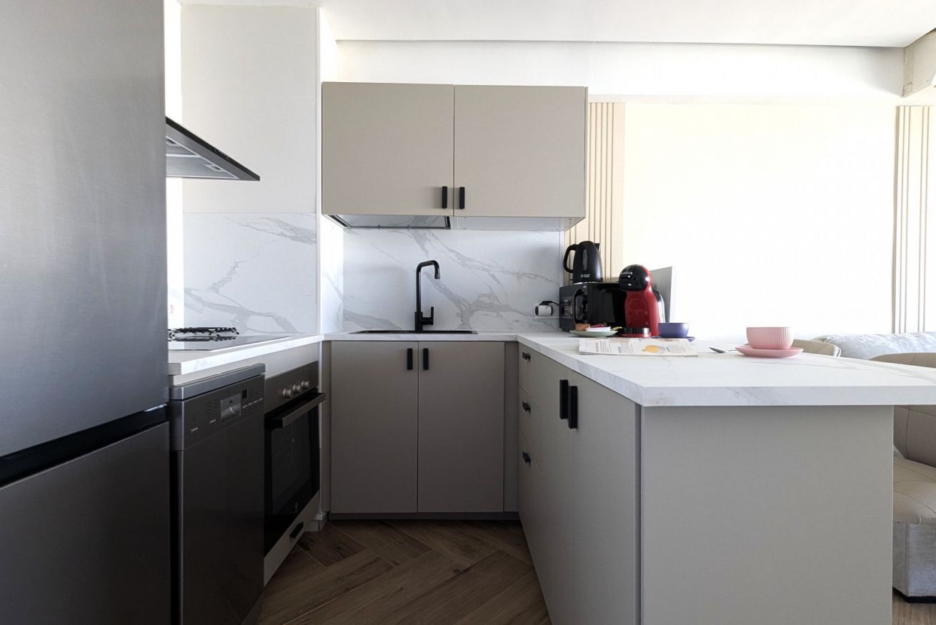 A compact kitchen with a built-in dishwasher, a stove, and a coffee maker.