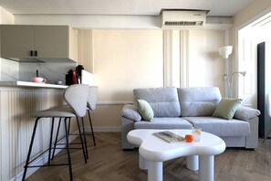 A modern living space with a kitchen area, a grey sofa, a white coffee table, and a bar stool. - PINTOR SOROLLA elegant apartment (Benidorm)
