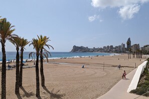 A beach with palm trees, a promenade, and a cityscape in the background. - PINTOR SOROLLA elegant apartment (Benidorm)