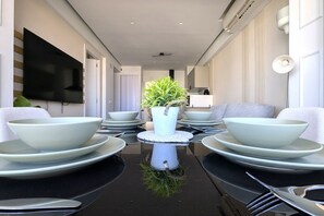 Un espace repas comprenant une table centrale, des chaises et un téléviseur fixé au mur.