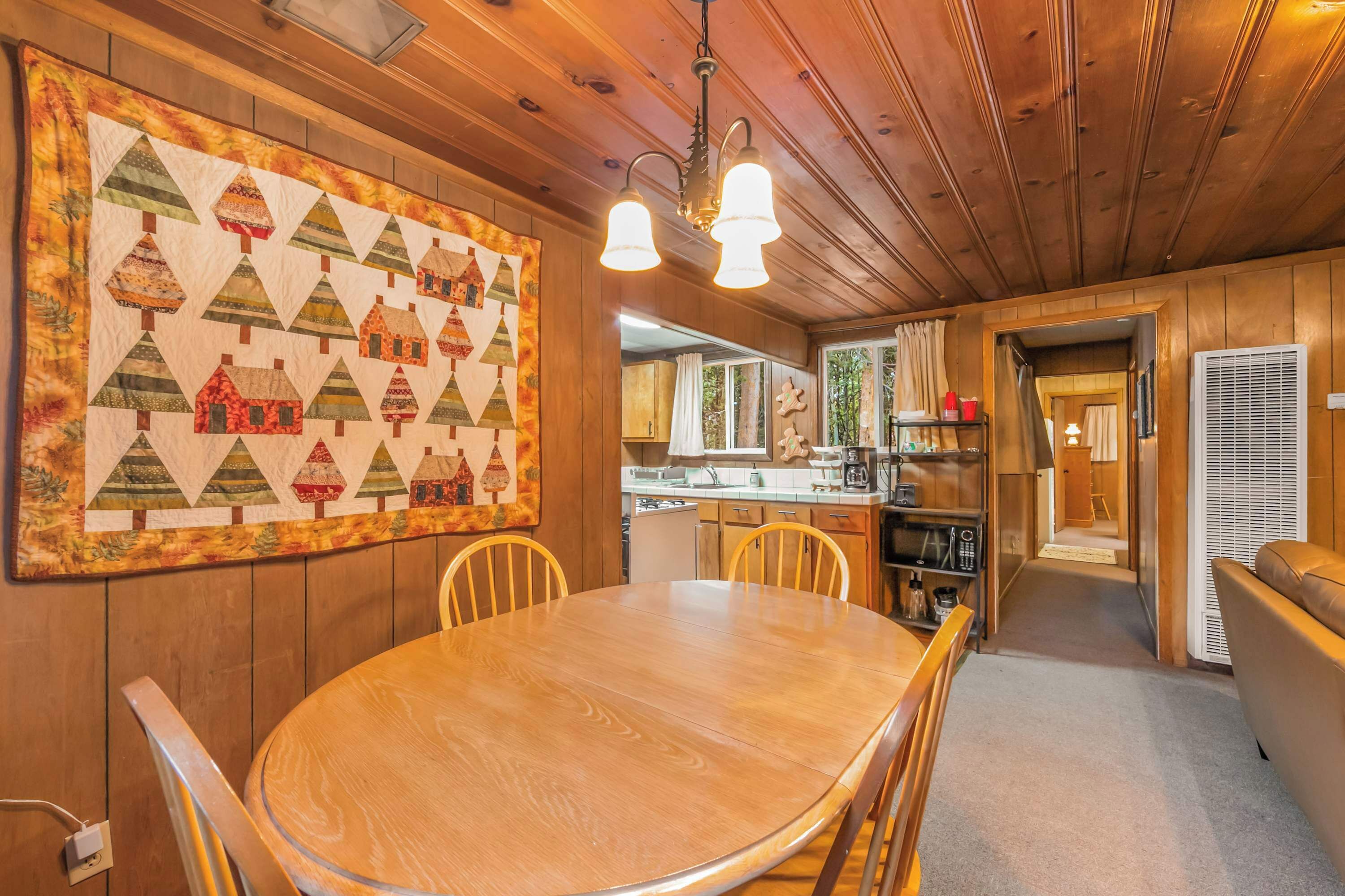 Ein Holzinterieur mit Esstisch, Stühlen, einer Küchenzeile und einer großen Stegdecke an der Wand.