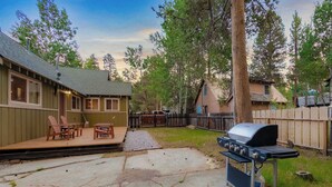 A backyard with a barbecue grill, outdoor seating, and a wooden deck. - Paradise Bungalow - Cozy Cabin Escape (South Lake Tahoe)