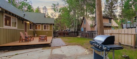 A backyard with a barbecue grill, outdoor seating, and a wooden deck.