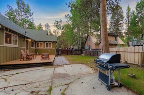 A backyard with a barbecue grill, outdoor seating, and a wooden deck. - Paradise Bungalow - Cozy Cabin Escape (South Lake Tahoe)