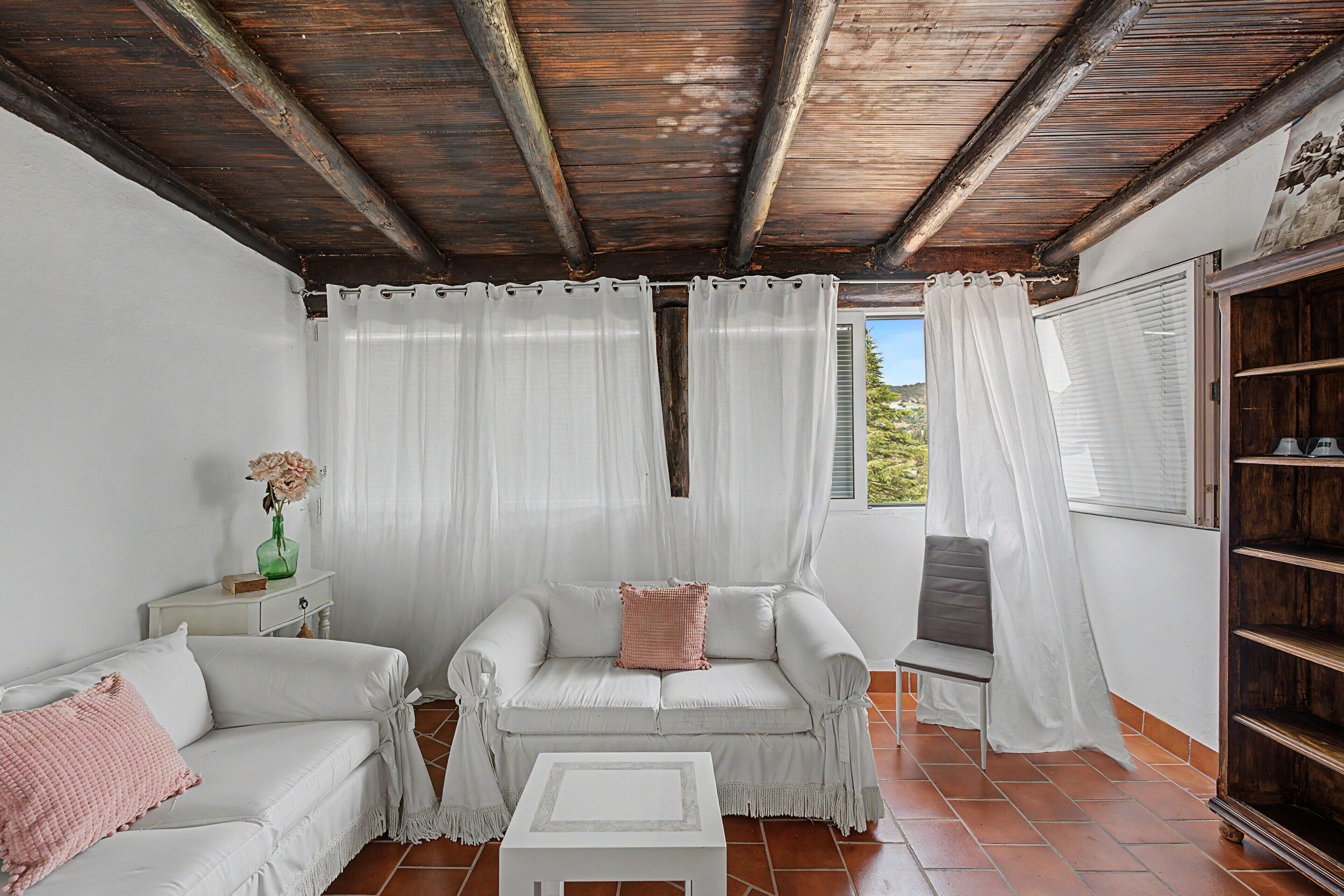 Un patio acogedor con un sofá blanco, una mesita y una estantería.
