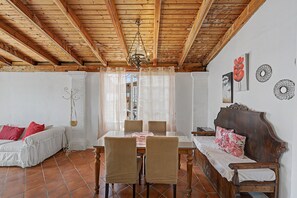 Uma sala de jantar com mesa de madeira, cadeiras e um candelabro.