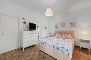 Una camera da letto con un letto, una cassettiera, una televisione e opere d'arte a parete.