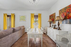 Zona pranzo con tavolo bianco, sedie e lampadario.