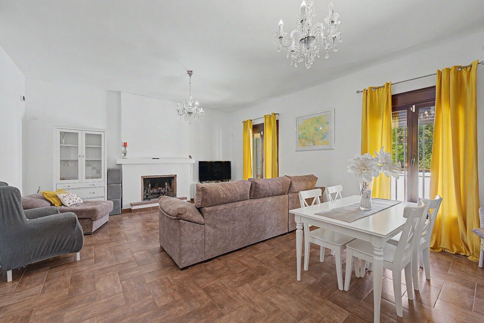 A living room with a fireplace, sofa, TV, and dining table.