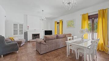 A living room with a fireplace, sofa, TV, and dining table.