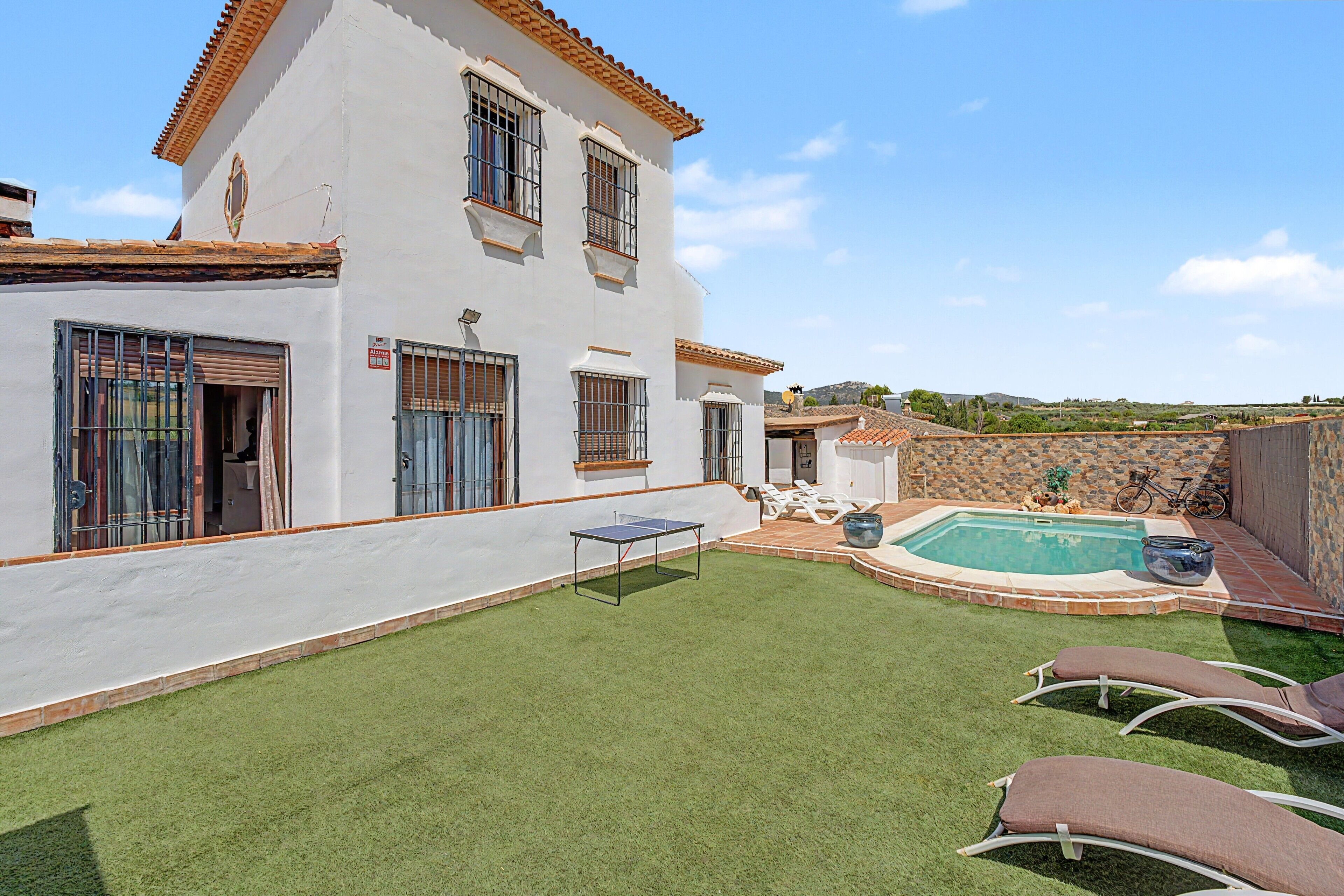 A house with a swimming pool, artificial grass, and a ping pong table.
