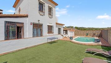 A house with a swimming pool, artificial grass, and a ping pong table.