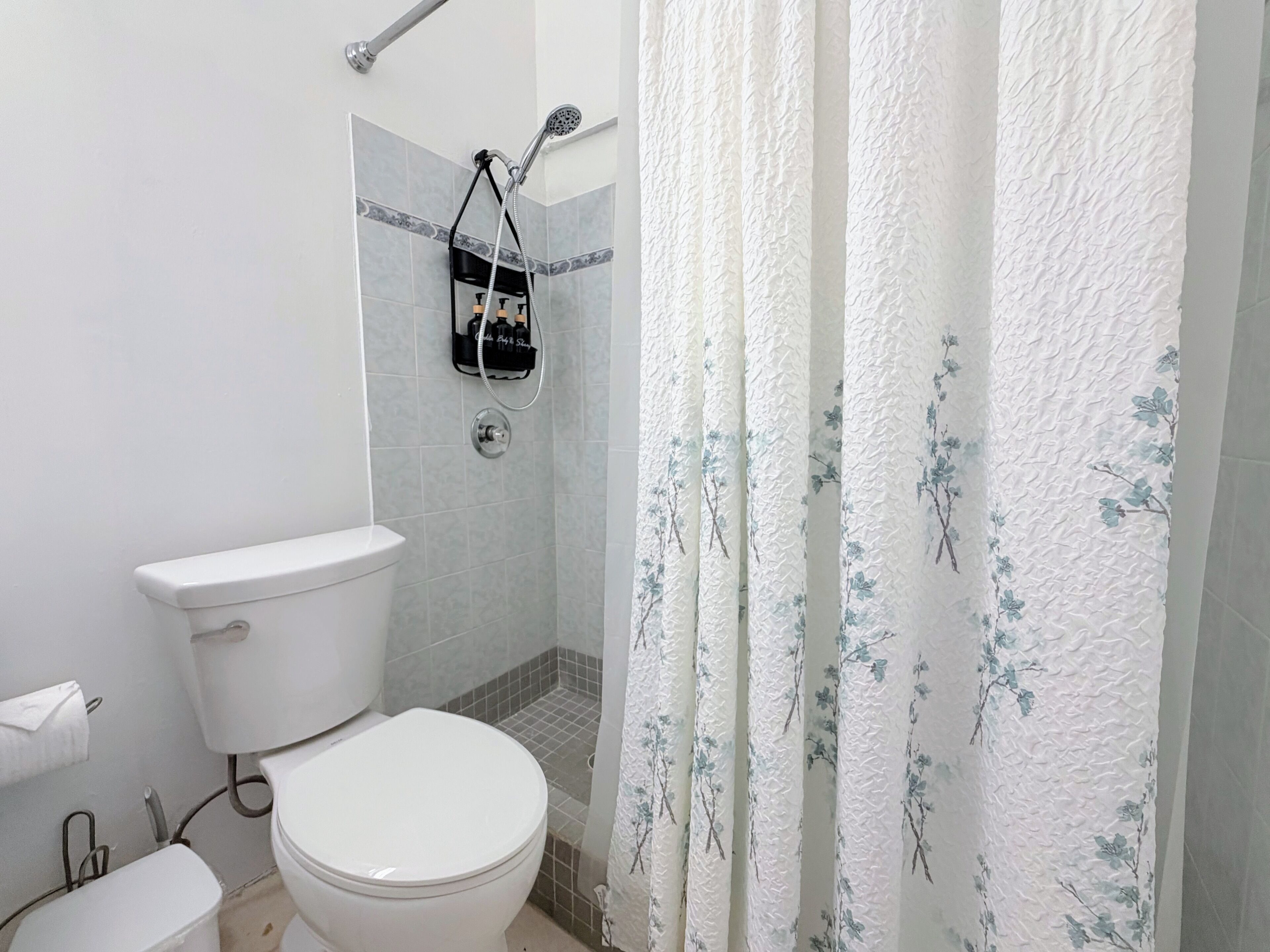 Een badkamer met toilet, douche en handdoekrek.