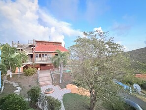 A multi-story building with a red roof, a staircase leading to a balcony, and a garden area with palm trees. - Remote Quiet Location Amazing Culebra Views (Ceiba)