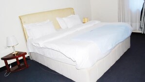 A standard hotel room with a single bed, a bedside table with a lamp, and a window with curtains. - KAA HIGHWAY HOTEL (Mukono)