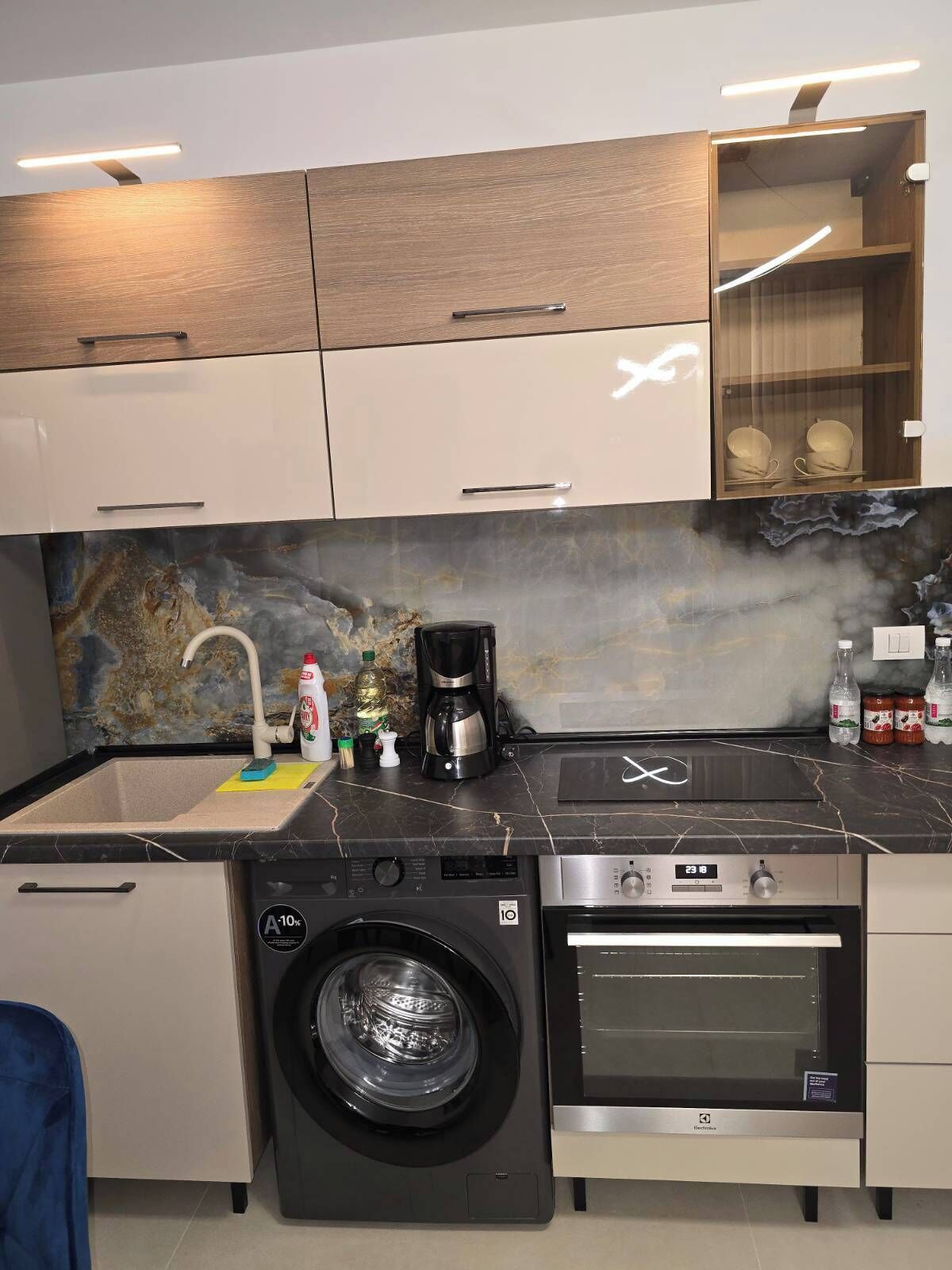 A compact kitchen with a washing machine, a coffee maker, and a microwave.