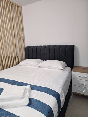 A bed with a dark headboard, white bedding, and a blue-striped blanket. - Costinești, 50 m to Nibiru, AC, wifi, tv, fully equipped kitchen, sea view (Costinești)