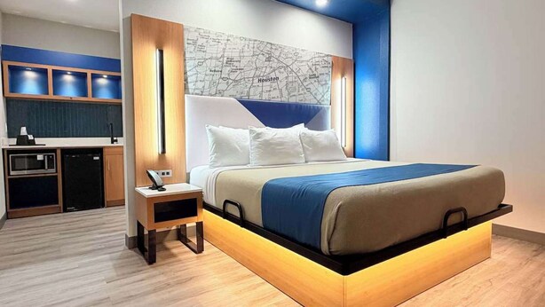 Een moderne slaapkamer met een bed, nachtkastjes, een kaart aan de muur en een kitchenette.