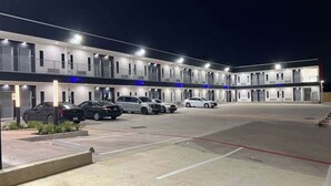 Een hotel met meerdere verdiepingen en een parkeerplaats.