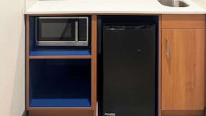 Een kleine keuken met een magnetron, vaatwasser en een spoelbak.