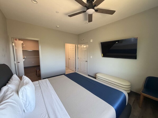 A hotel room with a bed, a ceiling fan, a TV, and a desk.