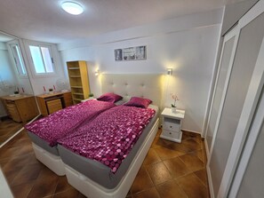 Ein Schlafzimmer mit Bett, Nachttischen, einem Kleiderschrank, einem Schreibtisch und einem Fenster.