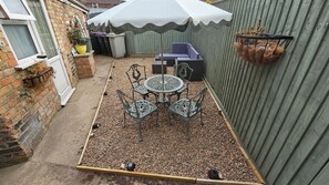 A patio with a table and chairs, a covered seating area, and a hanging plant basket. - Twisted Chimney View (Alford)