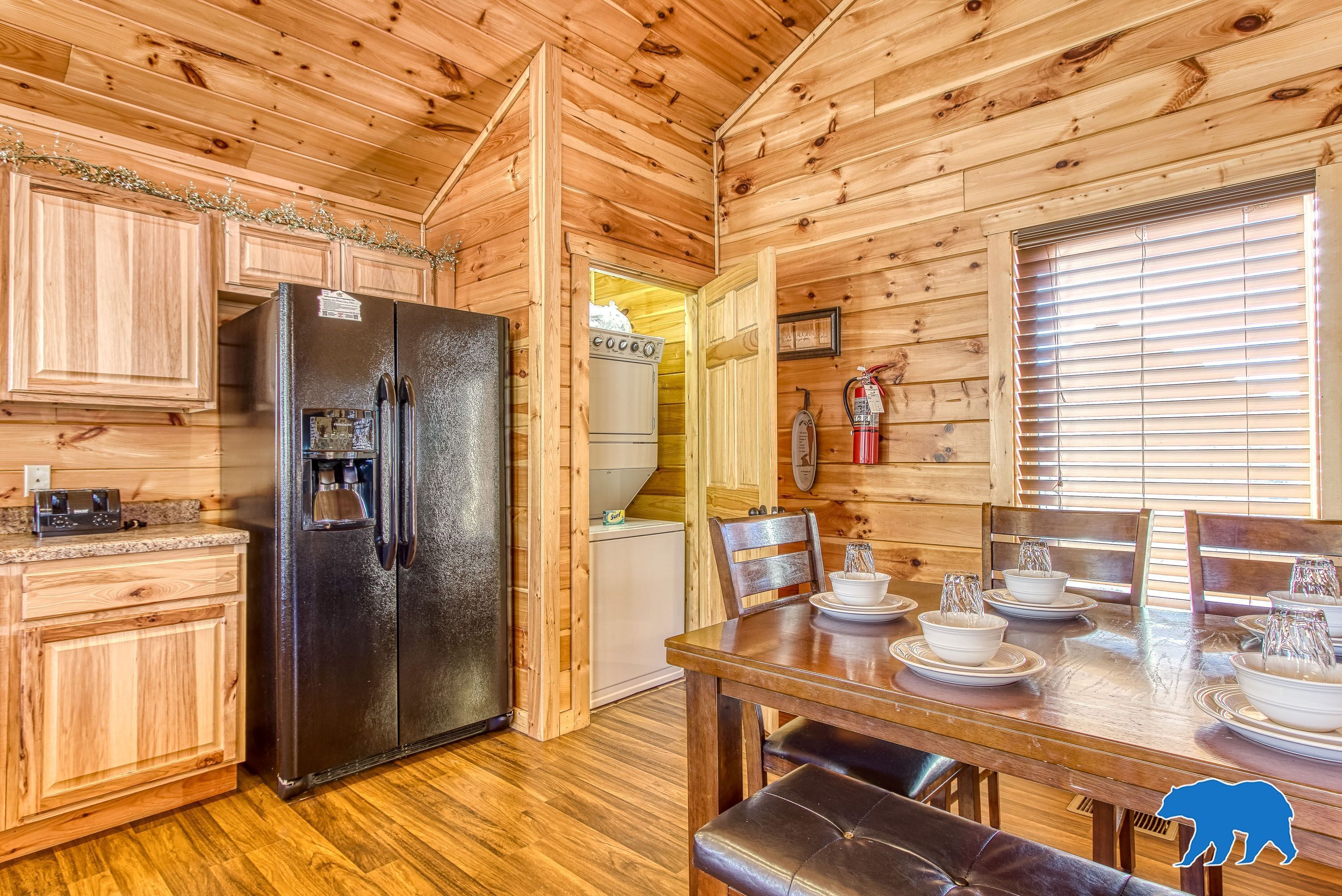 A wooden cabin interior with a kitchen, dining area, and a fireplace.