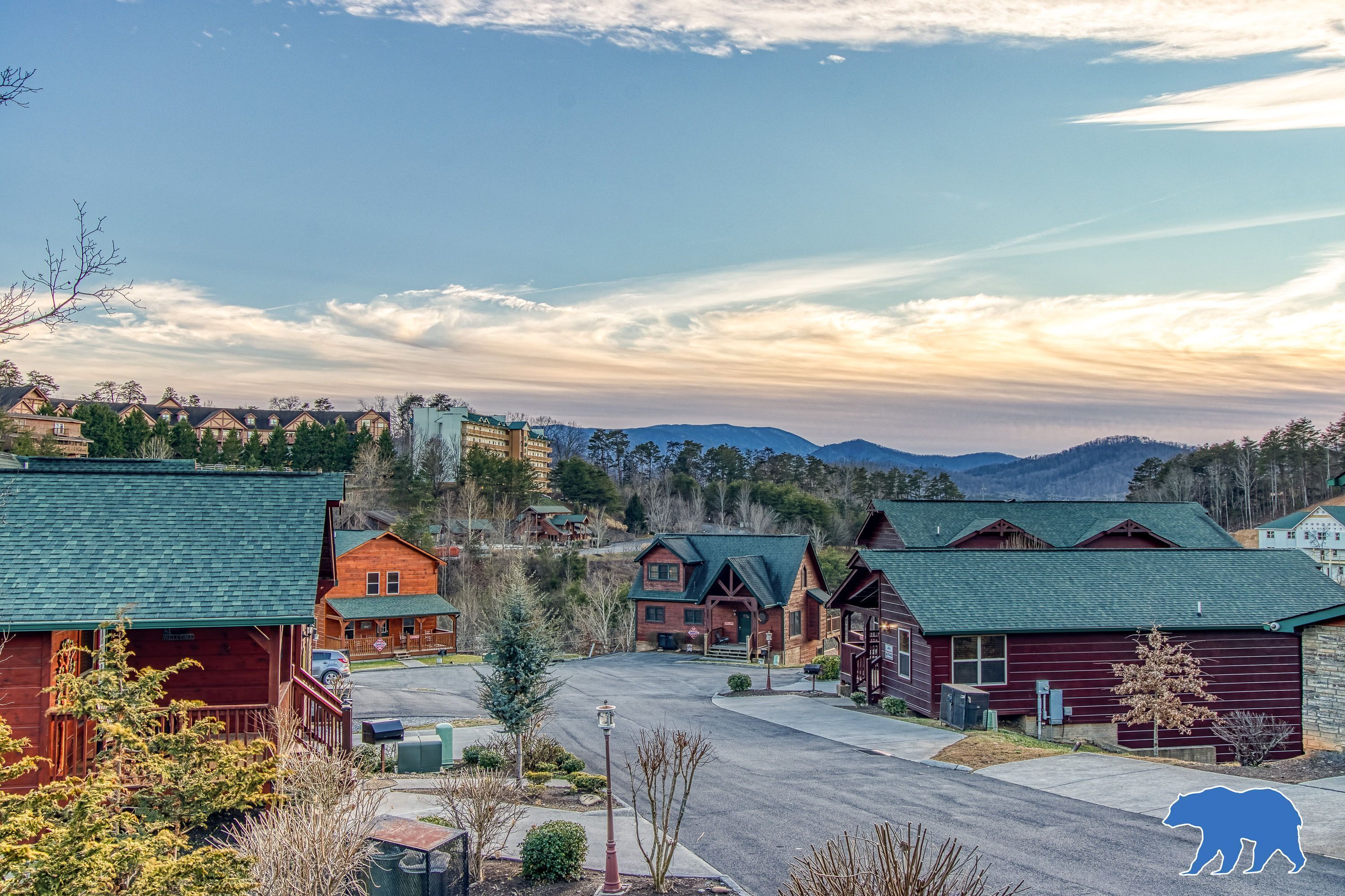 A residential area with multiple wooden houses, a clear sky, and mountains in the background.