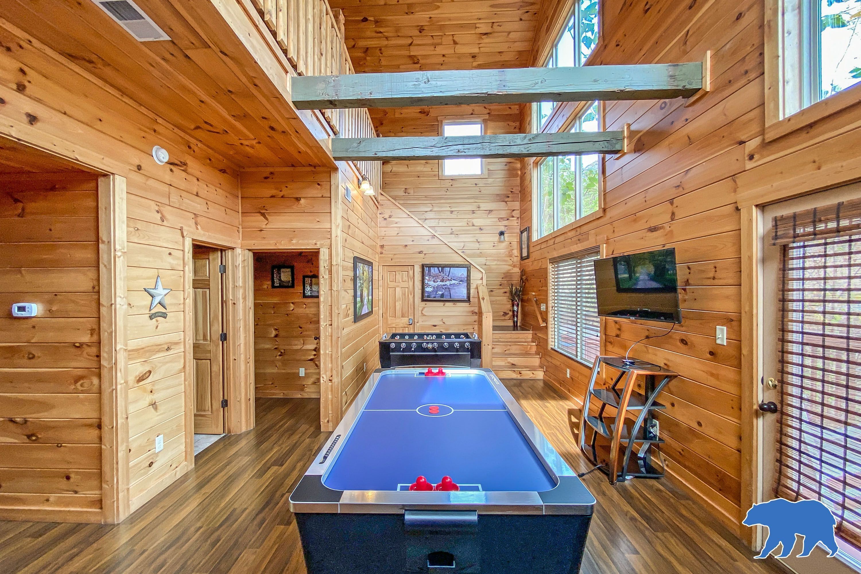 A wooden interior with a pool table, a television, and a bear logo.