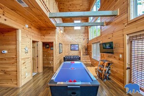 A wooden interior with a pool table, a television, and a bear logo. - Blue Bear Lodge in Pigeon Forge (Pigeon Forge)