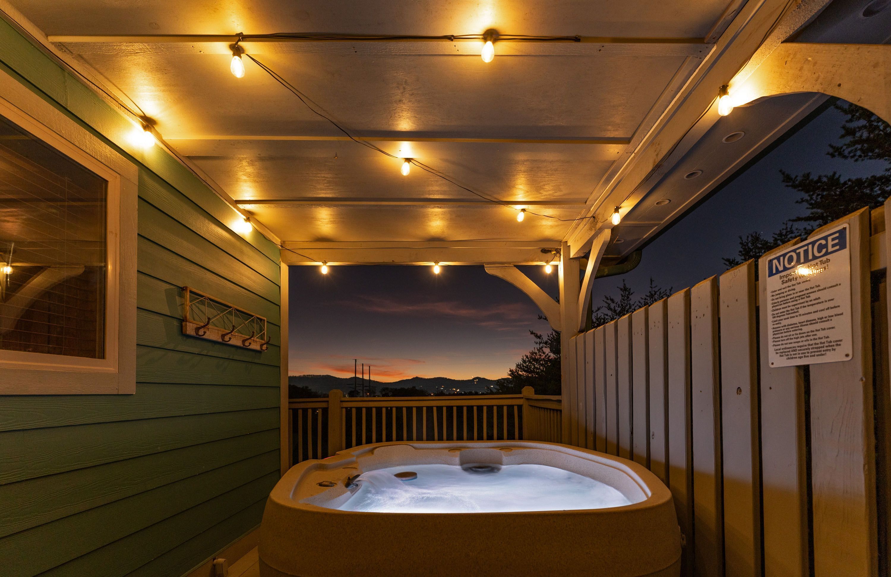A hot tub area with a sunset view, a wooden deck, and a safety notice sign.